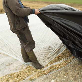 Medarbejder håndterer ensilagefolie på stakken